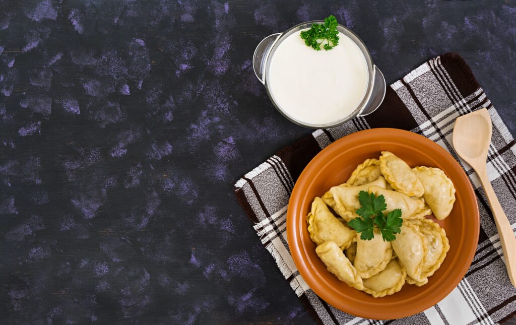 Delicious dumplings with cabbage on dark background. Top view