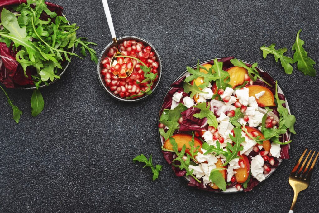 Fresh salad with arugula, radicchio, peaches, feta cheese and pomegranate seeds