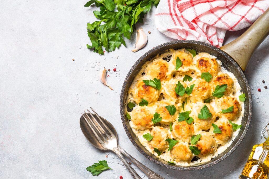 Meatballs in cream sauce with parmesan cheese top view.