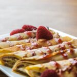 close-up view of sweet rolled pancakes with raspberries